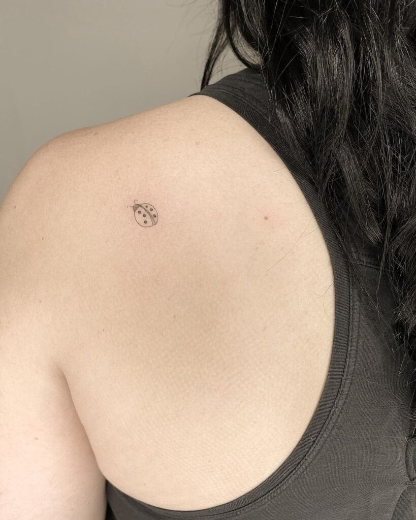 Little fineline tattoo above the shoulder ladybug whimsy
