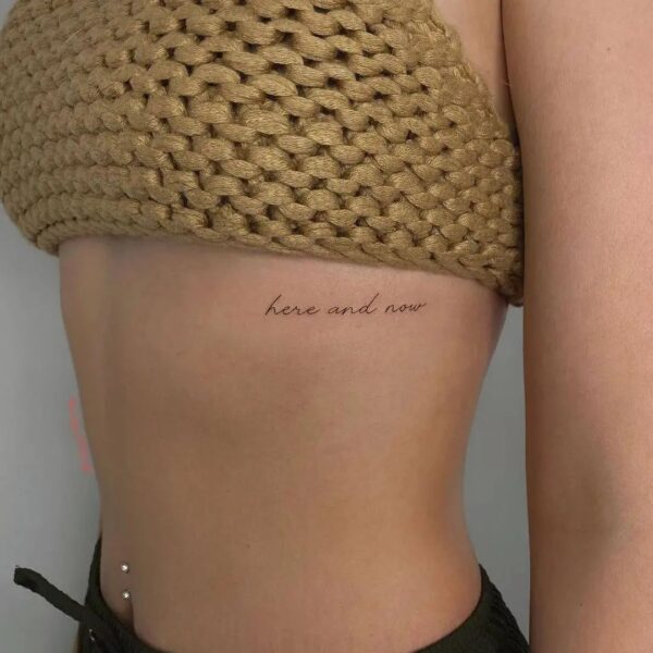 70 Stunning Rib Tattoo Ideas For Female November 2024   Tiny Script Lettering Here And Now Words Rib Tattoo A Subtle Reminder Present Moment 600x600 